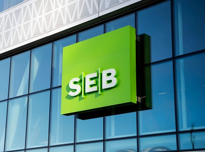 A green SEB bank sign mounted on the exterior of a modern glass building.