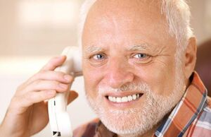 An older smiling man with white hair holds a white telephone receiver to his ear.