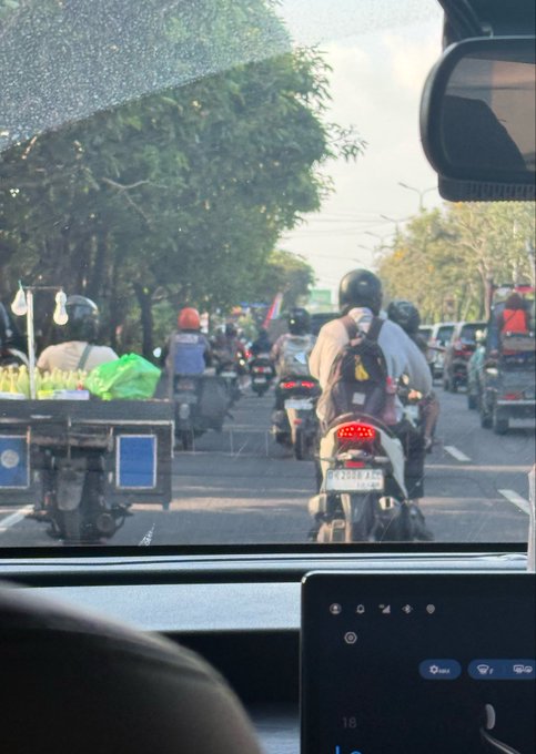 A photo taken from inside a car, showing a traffic jam in Bali with multiple motorcycles and scooters stopped on the road ahead. The scene captures the frustration of being stuck in congestion while the driver tops up their Binance Wallet for a $pPOLY (Polymarket's pre-IPO allocation) entry, highlighting the irony of hustling through Bali's notoriously chaotic traffic to secure one of only 7,000 available spots.