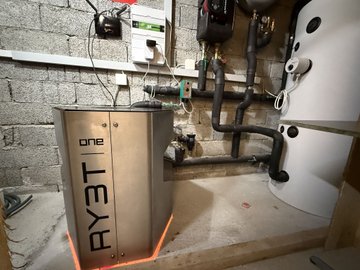 An open-source Bitcoin mining setup labeled "БУТ 19" is installed alongside a hot water tank and electrical panel, with software dynamically adjusting each miner's power draw between 1–3 kW to convert surplus solar energy into Bitcoin rather than exporting it to the grid.