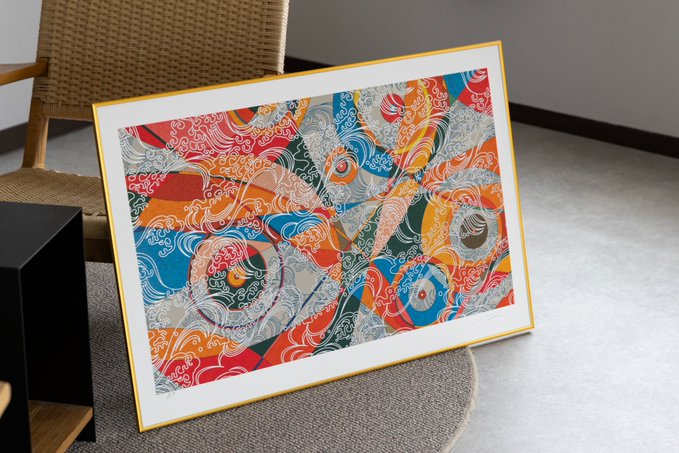 A framed abstract artwork featuring red, blue, orange, and white swirling designs leans against a woven chair.