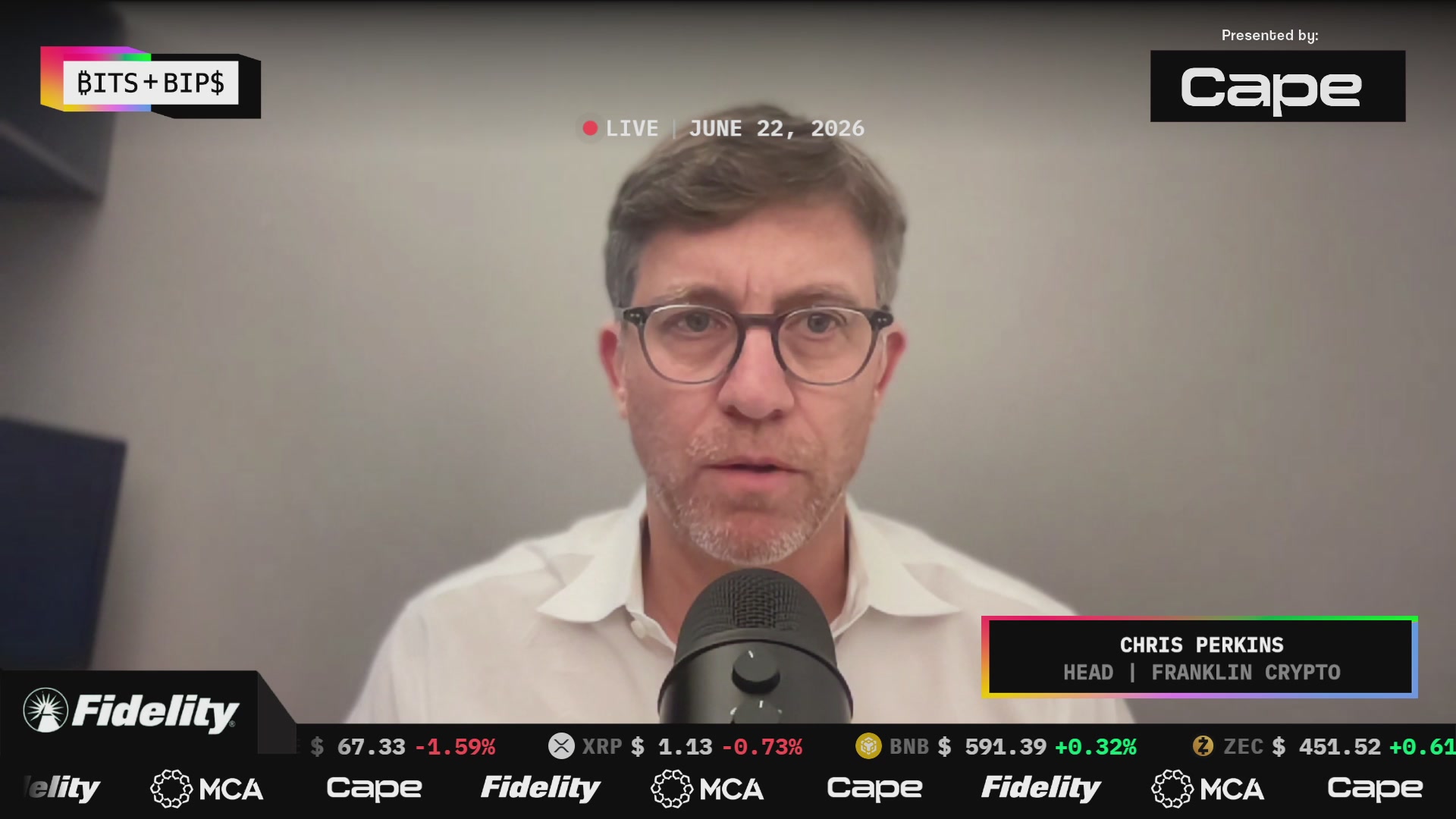 The image shows a man standing at a desk in front of a computer screen while wearing glasses and speaking into a microphone. The computer monitor displays an audio recording or live stream with multiple people present, including a man named Chris Perkins. The main focus is on the content related to cryptocurrency and the exchange rate fluctuations, indicating a news story or live event about the crypto market.