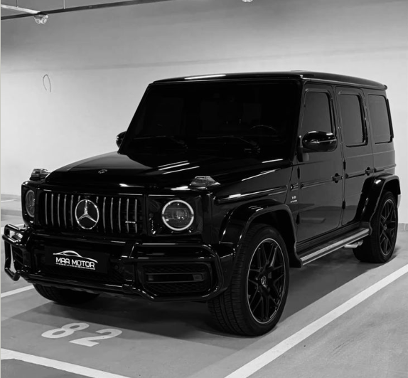 The image features a black Mercedes-Benz GLE SUV parked in a parking lot, with its front facing towards the camera. The car appears to be in excellent condition, as indicated by the clean exterior and well-maintained tires. The photo is taken from a low angle, which emphasizes the size of the vehicle and makes it look even more impressive.