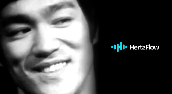 A black-and-white close-up portrait of a young man smiling, with the 'HertzFlow' logo displayed in blue on the right side.