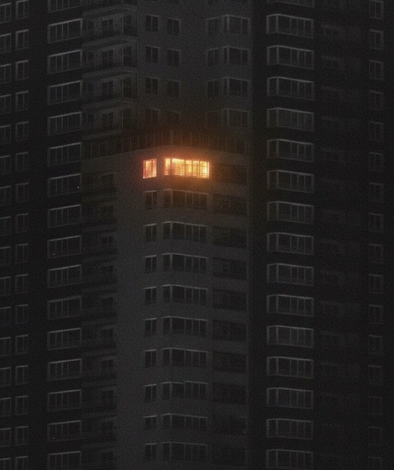 A lone, warmly lit apartment glows from an otherwise dark high-rise building at night, evoking a sense of isolated privacy in a sea of countless identical windows. The singular illuminated space visually mirrors the post's theme of confidentiality and selective disclosure, suggesting that even amid widespread exposure, one can keep their personal details hidden while still signaling presence.