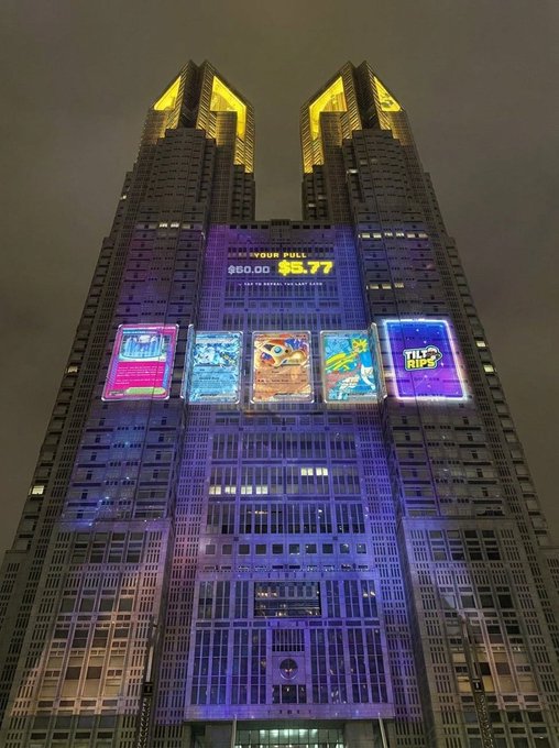 The Tokyo Shiba tower is illuminated at night with colorful LED displays featuring TILT! and other pack designs, alongside a jackpot counter showing "$0.00" and "$5.77." The vibrant projections align with the post's announcement of slamming $50 Premium Packs, reinforcing the excitement of opening rare packs to chase big wins.