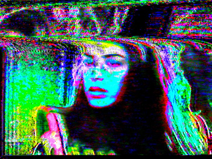 A heavily glitched and distorted portrait of a woman with her eyes closed, rendered in psychedelic magenta, green, and blue pixelated artifacts.