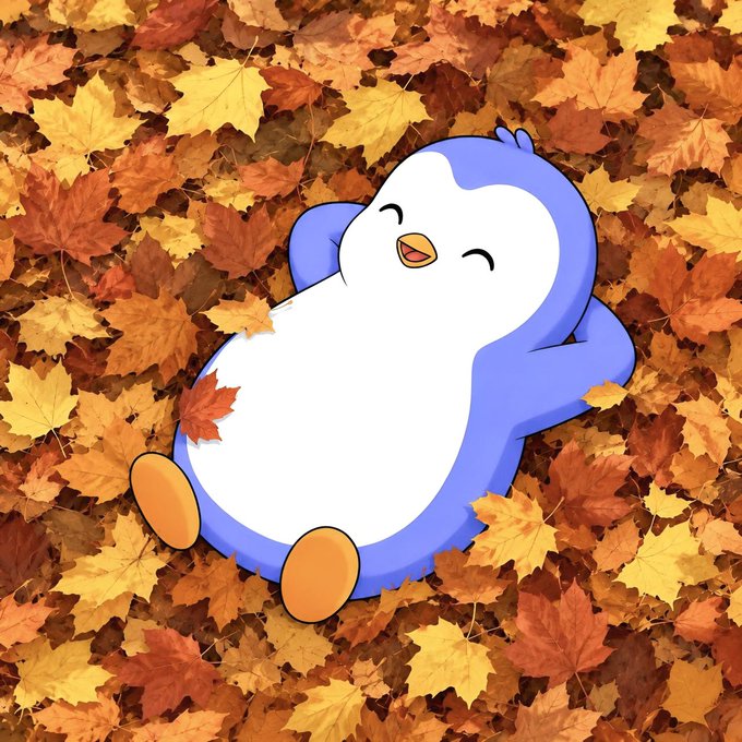 A cute blue and white cartoon penguin character with orange feet lies happily on its back in a bed of warm autumn leaves.