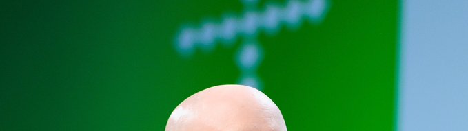A close-up of a fingertip hovers in front of a green screen displaying a blurred stock chart logo, representing the obscure "Mystery Stock #17" linked to pancakeswap.finance/stocks that users are challenged to identify.