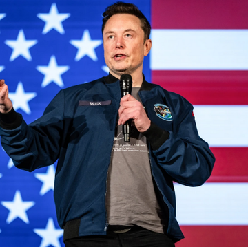 The image features a man wearing a blue jacket, standing in front of an American flag with his hands raised above his head as if he's speaking into a microphone. The caption below the image reads "SpaceX'S IPO valuation is expected to equal the entire Bitcoin and crypto market cap. Excluding stablecoins. [focus on what is in the image and how it relates to the post]".