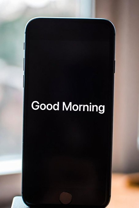 A black smartphone screen shows the phrase 'Good Morning' in white text.