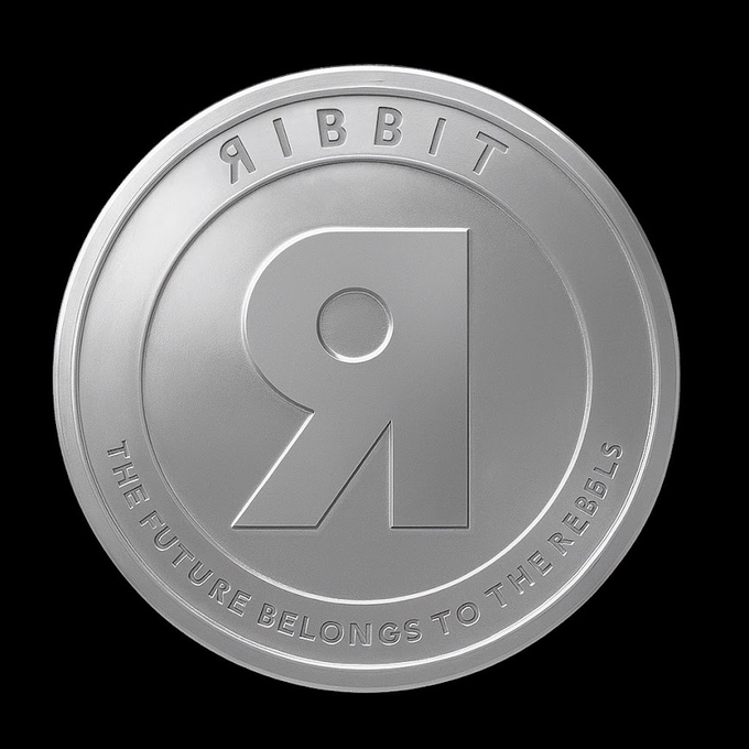 A silver coin against a black background featuring a large stylized 'R' in the center, with 'RIBBIT' engraved along the top and 'THE FUTURE BELONGS TO THE REBELS' along the bottom.
