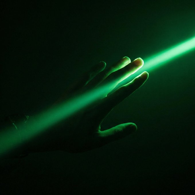 A hand reaches out to touch a single beam of green light in darkness, symbolizing an early investor's small, tentative grasp on the dawn of a bull market before the rest of the crowd follows the glow.