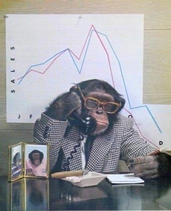 A humorous photo of a chimpanzee wearing glasses and a checkered blazer, sitting at a desk with a vintage telephone and a line chart showing sales data in the background.