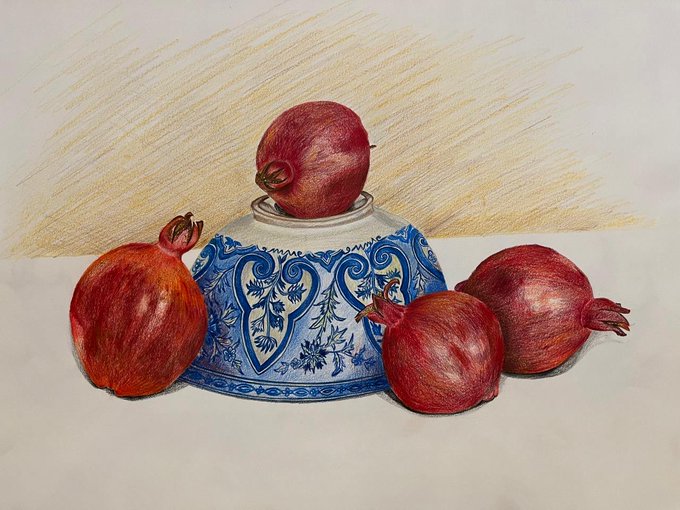 A colored pencil still life drawing showing four red pomegranates arranged around an ornately decorated blue and white porcelain jar on a cream-colored surface.
