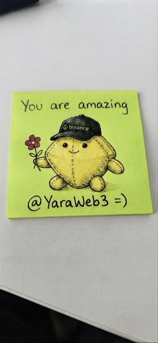 A hand-drawn sticky note on white paper featuring a cute yellow character wearing a black 'binance' cap and holding a pink flower, with the text 'You are amazing' and '@YaraWeb3 =)' written on a green background.