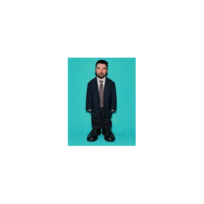 A small figure of a man in a black suit with a tie, standing against a teal background, appearing shrunken in scale.