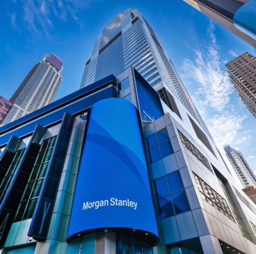 A towering skyscraper displays a prominent "Morgan Stanley" sign, with surrounding financial architecture emphasizing the presence of established banking institutions. The image of this major Wall Street firm visually anchors the post's discussion of tokenizing traditional financial assets, highlighting the contrast between legacy finance and the future vision of 24/7, programmable, and instantly-settled markets.