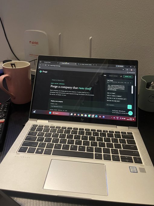 A silver HP EliteBook laptop sits on a desk displaying the 'Forge' website homepage, flanked by a pink mug and a white 'airtel' router in the background.