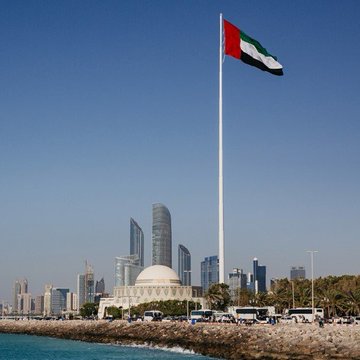 The UAE flag waves prominently over the Abu Dhabi skyline, symbolizing the nation's latest blockchain initiative as it partners with Avalanche ($AVAX) to upgrade its digital identity system for over 12 million UAE PASS users.