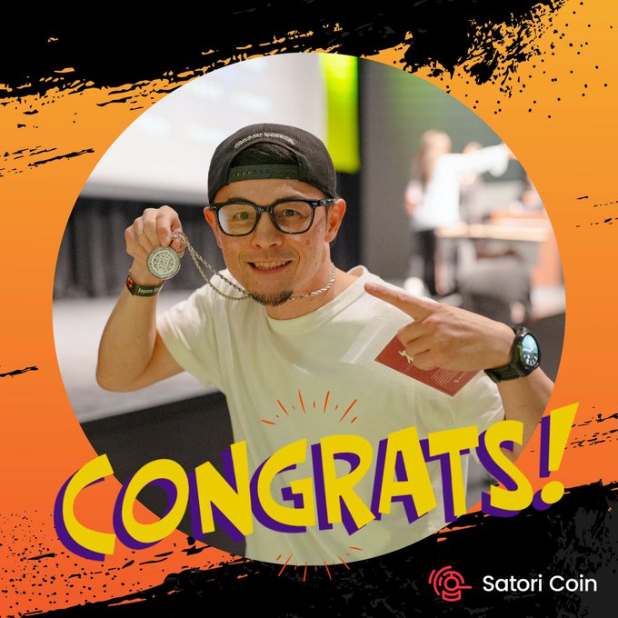 A congratulatory graphic from Satori Coin features a smiling man in glasses and a backwards cap proudly holding up a silver coin on a chain, with "CONGRATS!" displayed in bold yellow and purple letters.