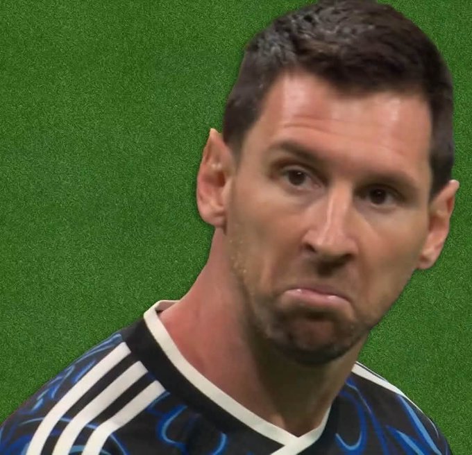 Lionel Messi displays a noticeably unimpressed, pouting expression while wearing a dark blue and black Inter Miami jersey. The image humorously captures his skeptical reaction to a fan's post jokingly backing Argentina over England in a betting bet on @1winToken.