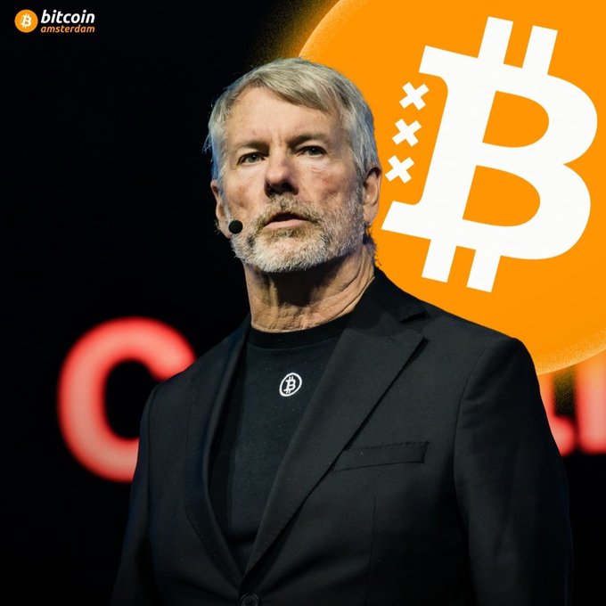A man with a gray beard speaking on stage at a Bitcoin Amsterdam event, with a Bitcoin logo visible behind him.