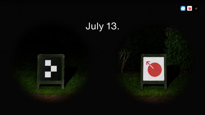 A dark image dated 'July 13.' showing two spotlights illuminating a checkered pattern and a red directional arrow sign on grass.