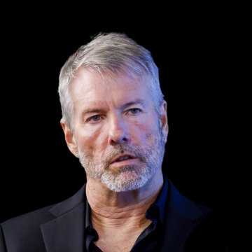A close-up photo of Michael Saylor against a black background, appearing serious as he speaks about his prediction that Bitcoin will fluctuate dramatically between $140,000 and $180,000.