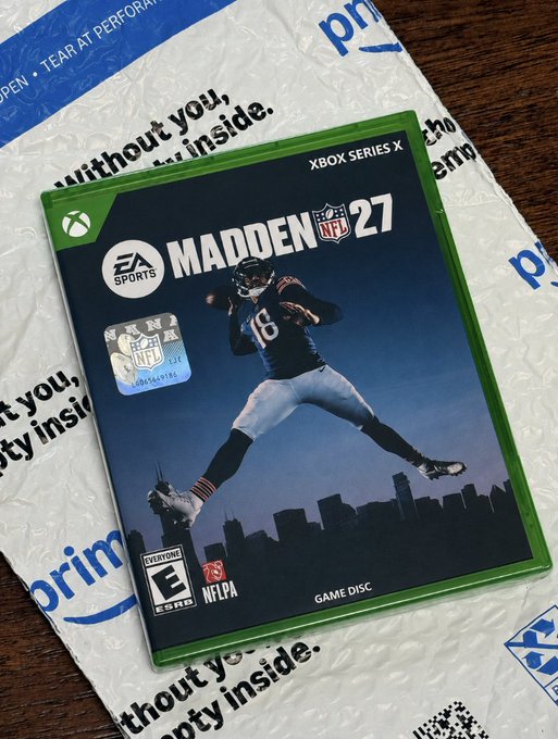 A new copy of Madden NFL 27 for Xbox Series X sits on top of an Amazon Prime shipping envelope, tying into the "paybox prime play" prompt by showcasing a gaming purchase delivered via Prime. The EA Sports cover features a quarterback in a Bears jersey (#16) against a Chicago skyline, rated E for Everyone.