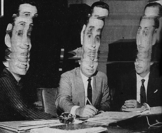 A distorted, glitch-effect black and white vintage photograph showing multiple overlapping faces of men in suits sitting at a table, appearing to be from the mid-20th century.