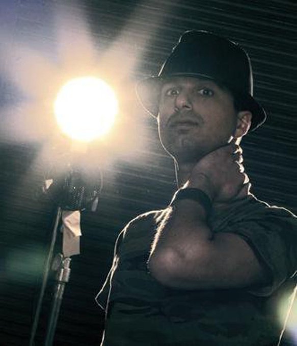 The image features a man wearing a black hat, standing next to a light source that appears to be a spotlight or a lamp. He has his arm around himself as he looks at the camera with an expression of surprise or curiosity. The background is dark, which emphasizes the subject and draws attention to him. The caption "GM if you gm $sol" suggests that this image might have been taken during a photoshoot or a similar event where the man's appearance was intentionally highlighted for a specific purpose.

The man in the image seems to be dressed casually, wearing a black hat and a shirt. His expression conveys a sense of surprise or curiosity as he looks at the camera. The dark background further accentuates his presence and adds depth to the scene.