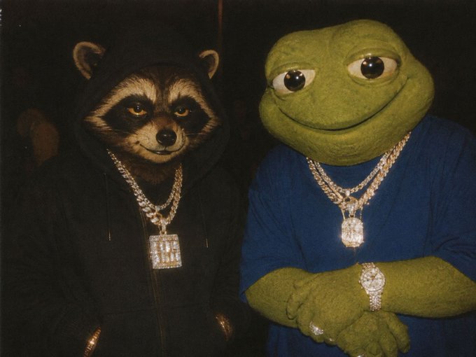 A photo of two figures wearing large diamond-encrusted chains: Rocket Raccoon in a black hoodie and Pepe the Frog in a blue shirt, both showing off their jewelry.