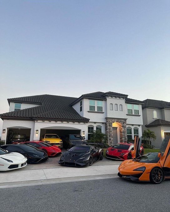 A row of luxury supercars—including Lamborghinis, Ferraris, and McLarens—sits parked in front of an opulent Mediterranean-style mansion, embodying the lavish lifestyle that crypto investors aspire to as cryptocurrency investments pay off handsomely.