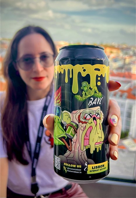 A woman holds a black beer can labeled 'BAK' and 'Mutantsbeer', Lisbon Apifest Edition, in front of a city backdrop.