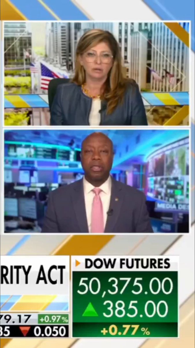The image shows two people, one woman wearing a suit and tie sitting behind a desk and the other man standing at the desk talking into a microphone during an economic debate or discussion. The screen displays various information about the stock market and trading activities, including price fluctuations and trading volume updates.