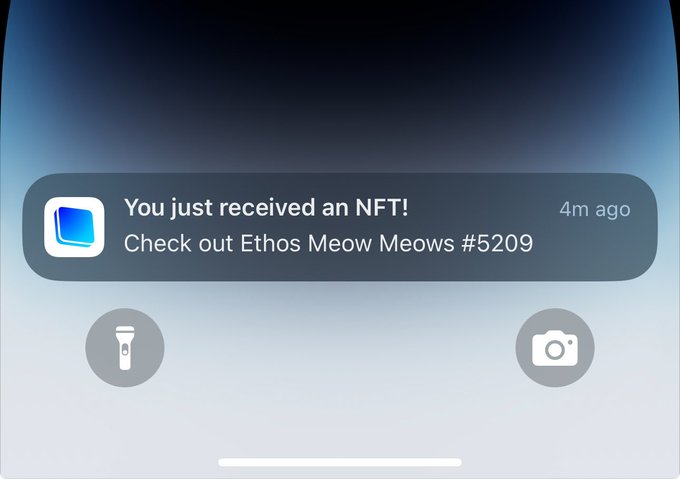 A smartphone notification reading 'You just received an NFT! Check out Ethos Meow Meows #5209' displayed on a dark-themed lock screen.