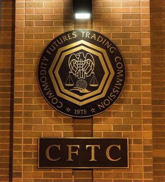 The image shows a "Commodity Futures Trading Commission" seal with the year 1975, mounted on a brick wall, along with a "CFTC" sign below it. This official emblem relates to the post by lending regulatory authority to the CFTC's warning about the risks of crypto ATMs, emphasizing the urgency of consumers being cautious due to the instant and irreversible nature of such transactions.