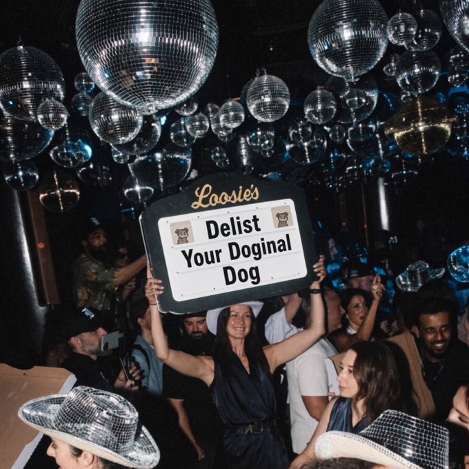 A woman in a disco setting full of disco balls holds up a sign reading 'Loosie's - Delist Your Doginal Dog'.