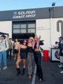 A blurry, low-resolution photo shows a group of people standing outside a building with a 'SOLAR' sign above the entrance.