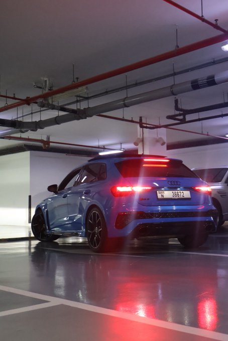 A blue Audi SUV with license plate "N 36612" is parked in an underground garage with its brake lights illuminated, suggesting it may be preparing to back out or maneuver in the space. The repeated "GN" in the caption likely stands for "good night," matching the quiet, dimly lit parking garage setting.