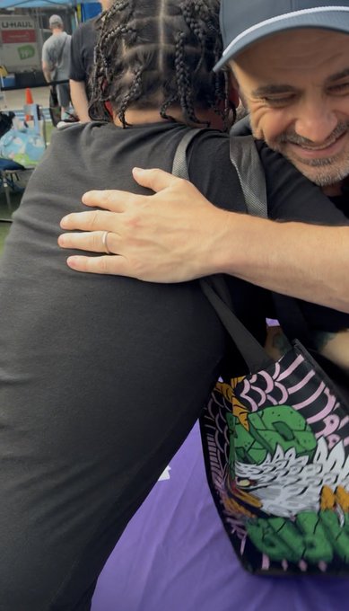 Two people share a warm hug at what appears to be a U-Haul event, with the man on the right wearing a gray cap while embracing a person with braided hair who carries a colorful bag. The post references a playful rock-paper-scissors game with Gary Vaynerchuk (@garyvee) and expresses gratitude for the memorable connection at the Veefriends gathering.