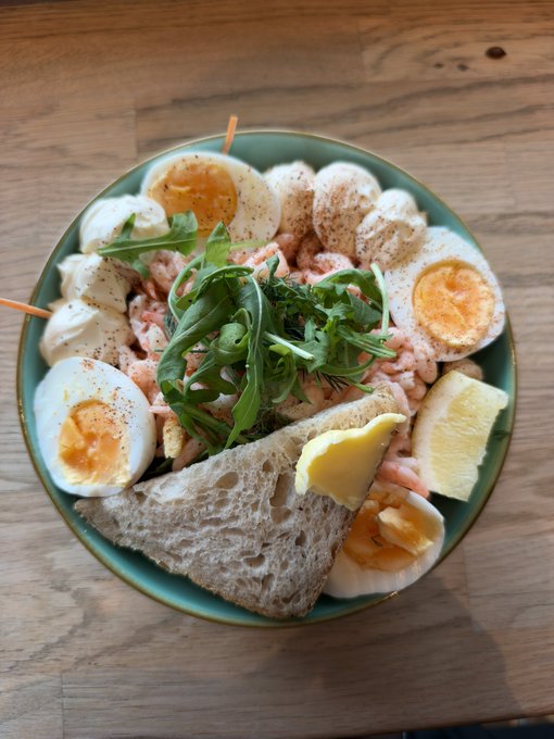 A plate of healthy food featuring soft-boiled eggs, shrimp, mozzarella slices, arugula, bread, and lemon, representing a wholesome break from indulgent eating. The image aligns with the post's message of choosing healthier meals after a week of indulgent eating, paired with a relaxed mindset for the weekend and a Bitcoin update ahead.