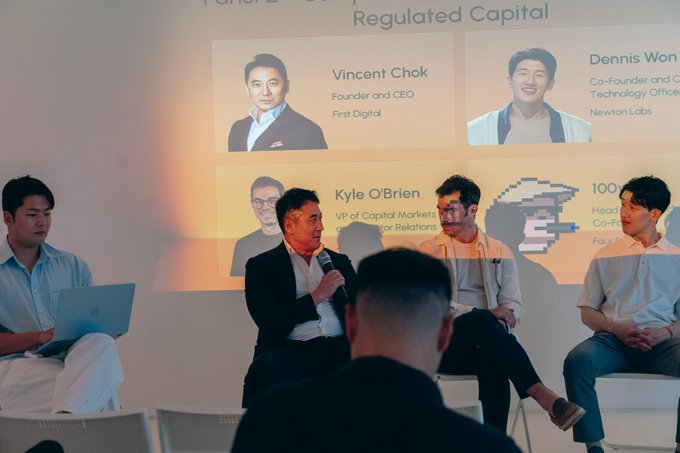 A panel discussion event where speakers are seated on stage with a backdrop displaying names including 'Vincent Chok, Founder and CEO, First Digital' and 'Kyle O'Brien, VP of Capital Markets' under the heading 'Regulated Capital.'