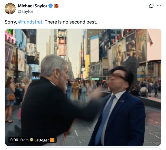 A tweet from Michael Saylor (@saylor) captioned "Sorry, @fundstrat. There is no second best" shows a video still in which a gray-haired man in a dark suit appears to strike another man in a blue suit and tie in Times Square, matching the post's claim of an AI video depicting Michael Saylor beating up Tom Lee.