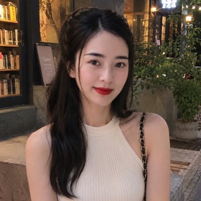A young woman with long dark hair poses for a photo outside what appears to be a bookstore or cafe at night.