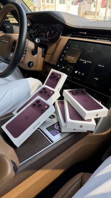 Four purple iPhone 18 Pro Max boxes are stacked on the center console of a luxury car interior, serving as visual proof of the giveaway prizes. The car's infotainment screen displays "No Bluetooth device open dialog" and "Advanced Media." The image reinforces the post's promise of 4 high-end iPhones being given away to lucky followers.