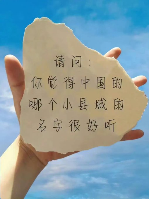A hand holding a torn paper with Chinese text reading '请问：你觉得中国的哪个小县城的名字很好听' (Question: Which small county town name in China do you think sounds nice?).
