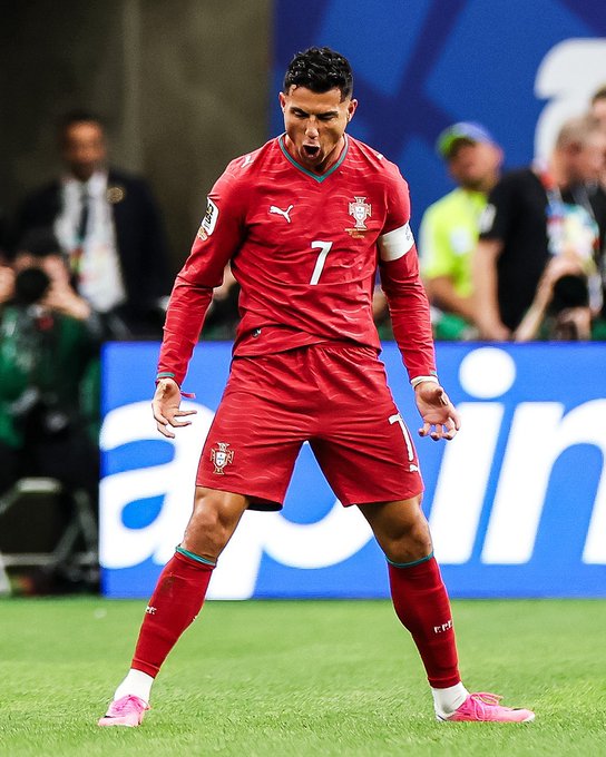 Cristiano Ronaldo, wearing Portugal's red #7 jersey, stands on the field with an intense, animated expression and clenched fists, channeling fierce determination ahead of a big match—a fitting visual for a hyped-up "GM" (good morning) energy. The Puma and Portugal federation logos are visible on his kit.