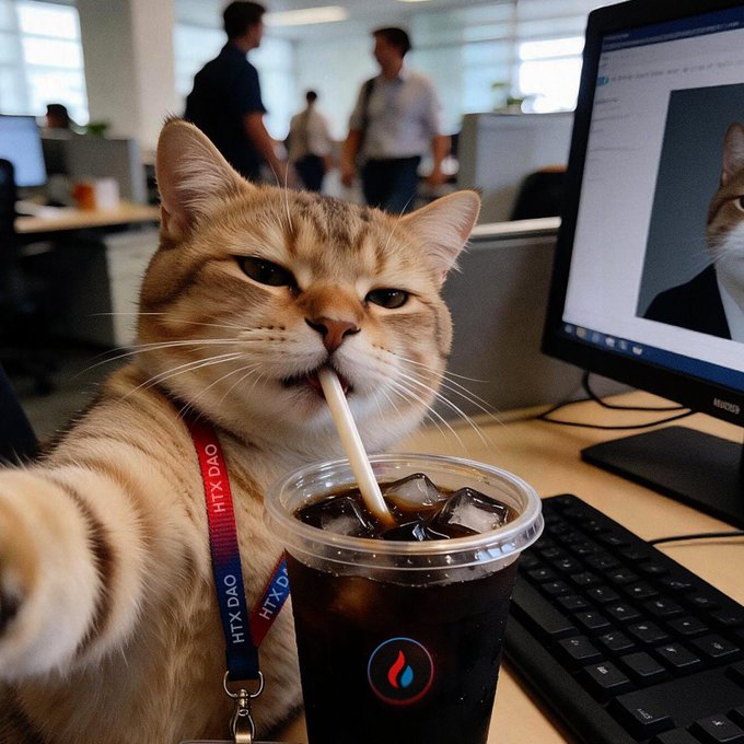 An orange tabby cat sipping iced coffee through a straw in an office setting, wearing an HTX DAO lanyard.